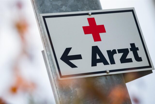 Ein Schild mit der Aufschrift „Arzt“ hängt an einer Straßenlaterne