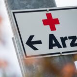 Ein Schild mit der Aufschrift „Arzt“ hängt an einer Straßenlaterne