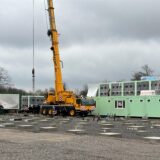 Mit Hilfe eines Krans werden Container aufgebaut.