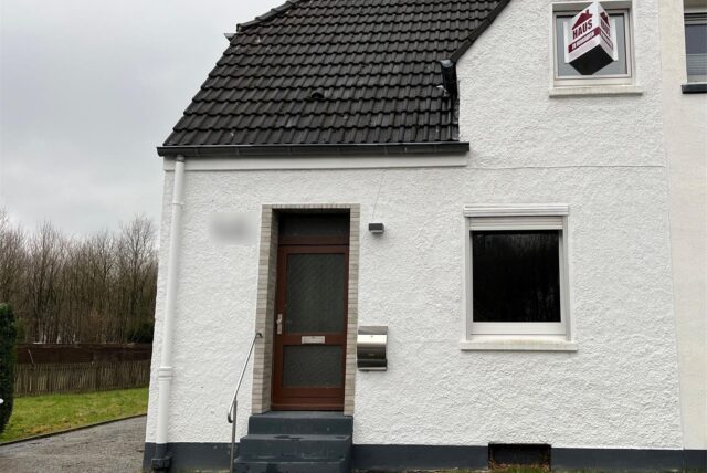 Blick auf die weiße Fassade einer Doppelhaushälfte in Herten-Bertlich, links ist ein Stück der Rasenfläche des dazugehörigen Gartens zu sehen.