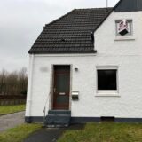 Blick auf die weiße Fassade einer Doppelhaushälfte in Herten-Bertlich, links ist ein Stück der Rasenfläche des dazugehörigen Gartens zu sehen.
