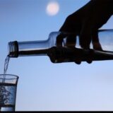 Eine Person schüttet Wodka aus einer Flasche in ein Glas.