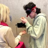 Ein Schüler der Achtenbeckschule in Herten trägt eine dunkle Brille, hält eine Geldbörse in der rechten und eine Münze in der linken Hand.