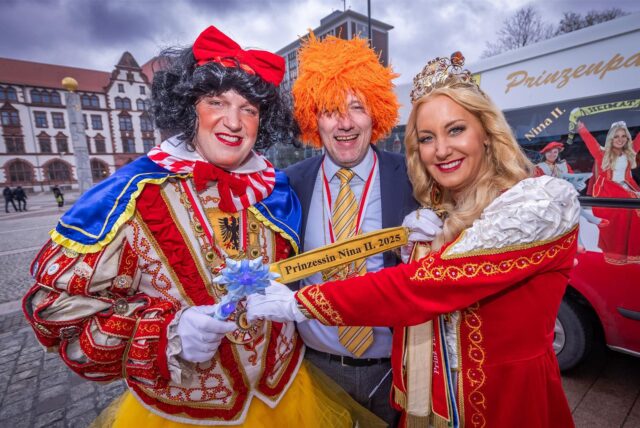 Prinzessin Nina die Zweite steht mit zwei verkleideten Männern auf dem Dortmunder Friedensplatz.