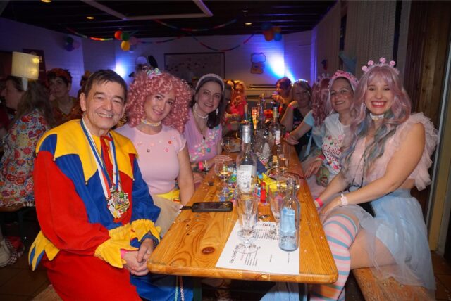 Menschen in Kostümen lachen in die Kamera.