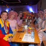 Menschen in Kostümen lachen in die Kamera.