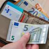 Eine Frau hält in ihrer Hand eine Brieftasche mit Geld und Bankkarten.