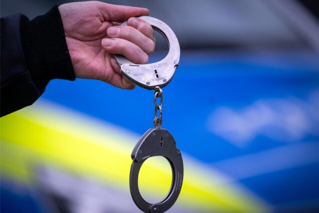 Ein Polizist hält Handschellen in der Hand.