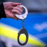 Ein Polizist hält Handschellen in der Hand.