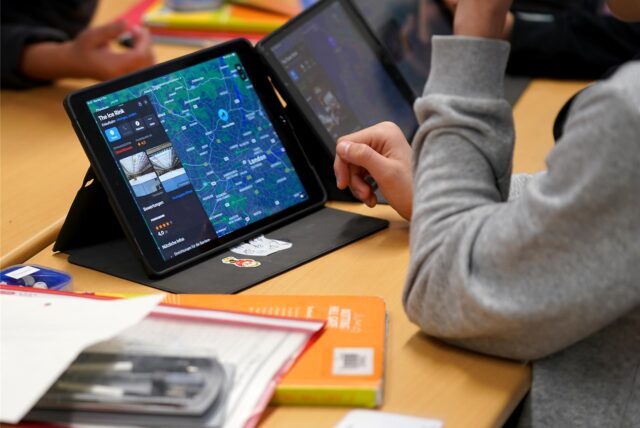 Ein Schüler sitzt im Unterricht vor einem Tabletcomputer.