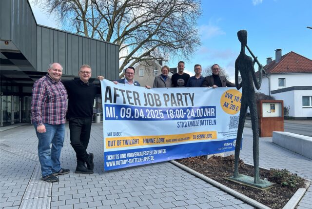 Sieben Personen stehen vor der Stadthalle Dattelns und halten ein Plakat mit der Aufschrift After Job Party hoch.
