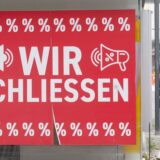 Am Schaufenster eines Geschäftes hängt ein Schild mit der Aufschrift. „Wir schließen“.