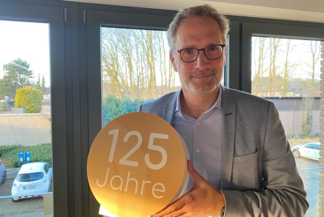 Thorsten Rattmann, Geschäftsführer der Hertener Stadtwerke, hält ein Jubiläums-Logo in den Händen.