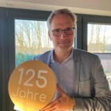Thorsten Rattmann, Geschäftsführer der Hertener Stadtwerke, hält ein Jubiläums-Logo in den Händen.