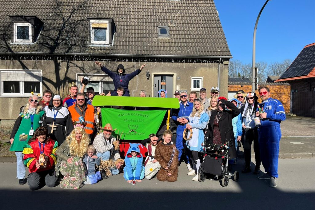 Bunt verkleidete Menschen stehen vor einem Haus. Bunt verkleidete Menschen stehen vor einem Haus.
