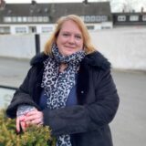 Ein Porträt von Yvonne Steinmüller, die in Herten-Westerholt an einer Hecke steht, auf der sie beide Hände angelegt hat.