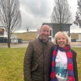 Wolfgang Heller und Anne Krüger stehen auf einer grünen Wiese, im Hintergrund ist die Zeche Erin.