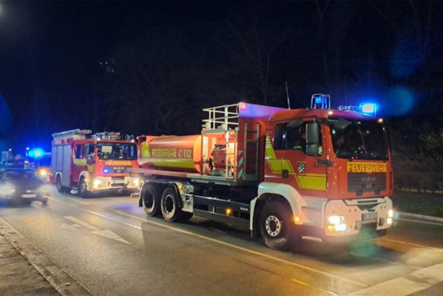 Feuerwehrleute arbeiten mit einem Löschschlauch vor der LWL-Klinik.