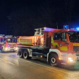 Feuerwehrleute arbeiten mit einem Löschschlauch vor der LWL-Klinik.