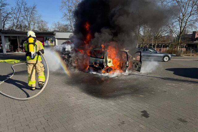 Ein Feuerwehrmann löscht unter Atemschutz zwei brennende Autos auf einem Parkplatz in Dorsten.
