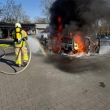 Ein Feuerwehrmann löscht unter Atemschutz zwei brennende Autos auf einem Parkplatz in Dorsten.