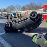 Unfall auf der A2: Ein Pkw liegt kopfüber auf der Straße. Im Hintergrund stehen Rettungskräfte.