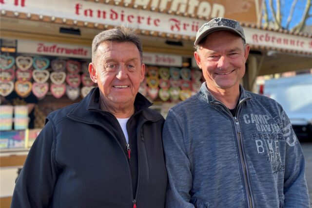 Richard Abendroth (1. Vorsitzender des Schaustellervereins Recklinghausen) und Thorsten Philipp (Schausteller) stehen vor Stand mit gebrannten Mandeln