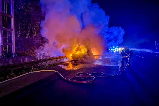 Einsatzkräfte der Feuerwehr löschen den brennenden Pkw auf der A40 in Dortmund.