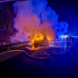 Einsatzkräfte der Feuerwehr löschen den brennenden Pkw auf der A40 in Dortmund.