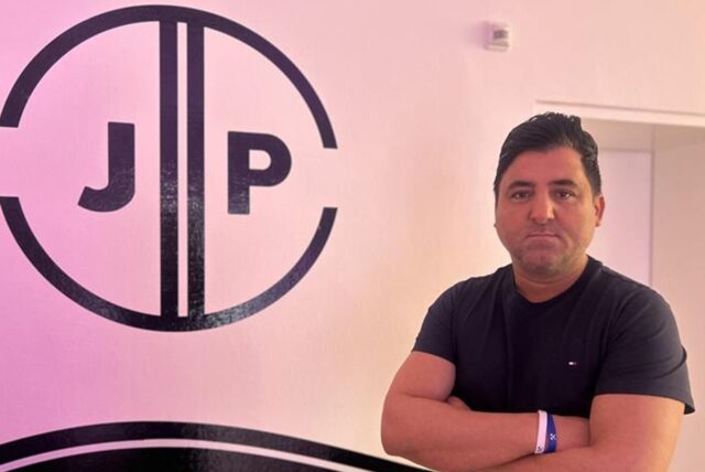 Cemil Duran steht neben dem Logo der JP-Fahrschule in Castrop-Rauxel.