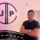 Cemil Duran steht neben dem Logo der JP-Fahrschule in Castrop-Rauxel.