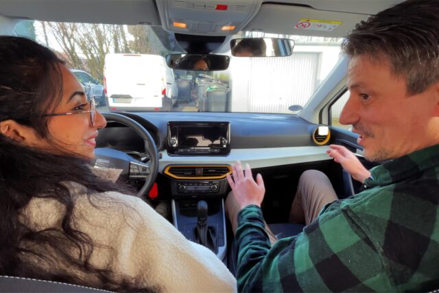 Der Hertener Fahrlehrer Sebahattin Altunsoy sitzt rechts neben Autorin Rosi Taslima Azam in einem Auto.