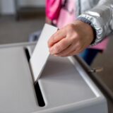 Eine Person wirft einen Stimmzettel in eine Wahlurne.