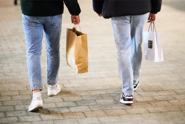 Zwei Passanten laufen am verkaufsoffenen Sonntag mit Einkaufstaschen durch die Innenstadt.