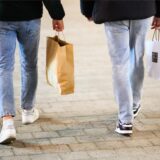 Zwei Passanten laufen am verkaufsoffenen Sonntag mit Einkaufstaschen durch die Innenstadt.