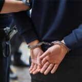 Mann in Handschellen wird von Polizei abgeführt.