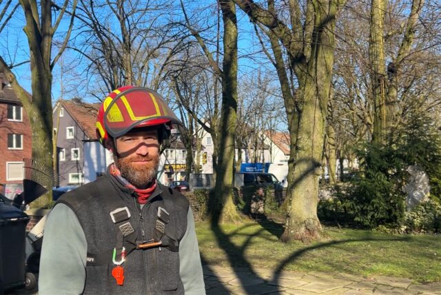 Ein Mann mit rotem Helm und Weste steht auf dem Vorhof der St.-Marien-Kirche in Waltrop.