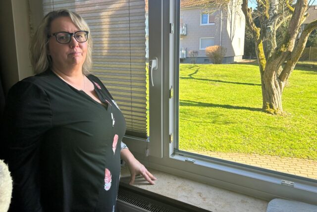 Melanie Huck steht vor ihrem geöffneten Wohnzimmerfenster in der Dogewo-Siedlung in Eving.