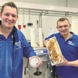 Zwei junge Männer mit Eis im Fünf-Liter-Behälter und im kleinen Becher.