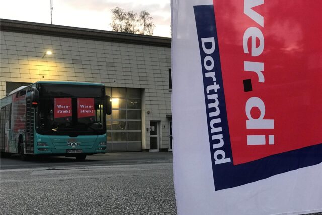 Ein Bus steht auf einem Betriebshof. In der Scheibe steht auf zwei Zetteln „Warnstreik“.