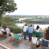 Besucher stehen im Biergarten am Jagdhaus Schellenberg in Essen und blicken auf den Baldeneysee.