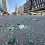 Scherben einer grünen Bierflasche liegen auf einer Straße.
