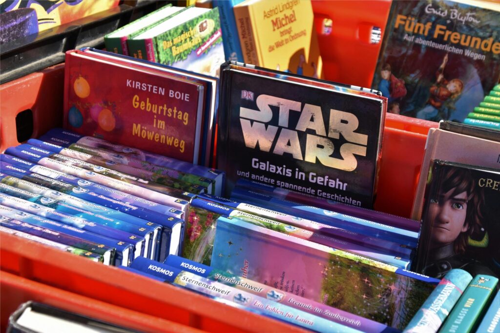 Auf einem Trödelmarkt stehen Kisten gefüllt mit gebrauchten Kinderbüchern. Auf einem Trödelmarkt stehen Kisten gefüllt mit gebrauchten Kinderbüchern.