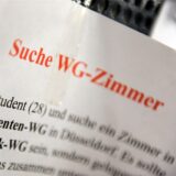 Ein Zettel mit der Aufschrift „Suche WG-Zimmer“ hängt an einem Schwarzen Brett in der Universität in Düsseldorf. (Archivbild)