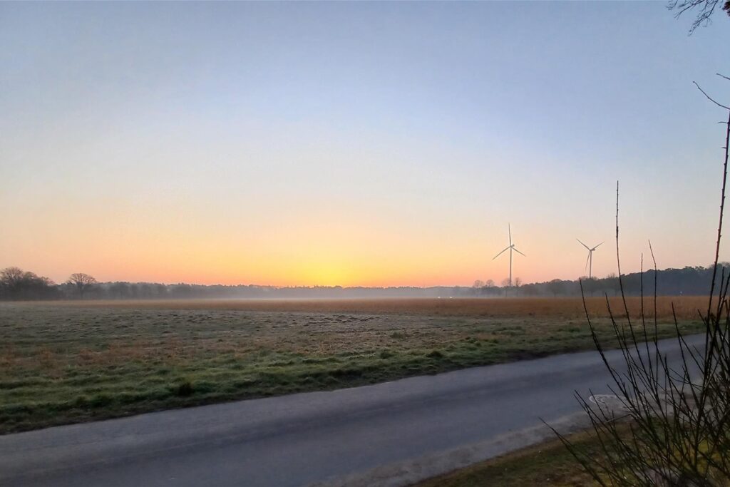 Sonnenaufgang über einer Wiese mit Windrädern und leichtem Nebel im März 2025 in Haltern.