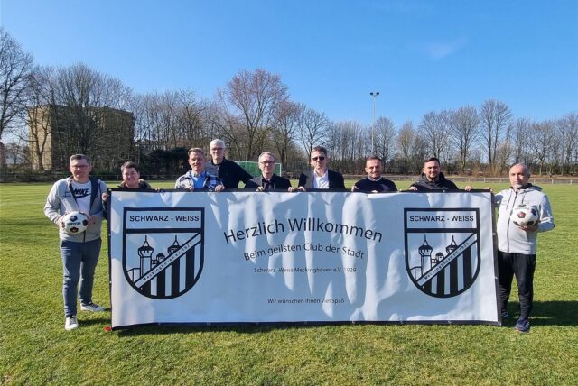Mehrere Personen stehen auf einem Rasen-Fußballplatz in Datteln und halten ein großes Banner hoch.
