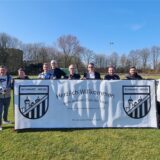 Mehrere Personen stehen auf einem Rasen-Fußballplatz in Datteln und halten ein großes Banner hoch.
