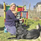 Tagesmutter Jennifer Krieger mit Sohn Quentin im Garten. Davor hockt Hund „Arti“.