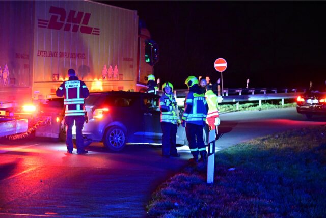Feuerwehrleute stehen um einen verunfallten Pkw.