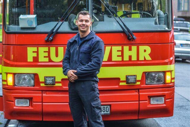 Feuerwehrmann Romano Bredehorn, der bei Temptation Island 2025 als Verführer teilnimmt, steht vor einem Wagen der Feuerwehr Dortmund.